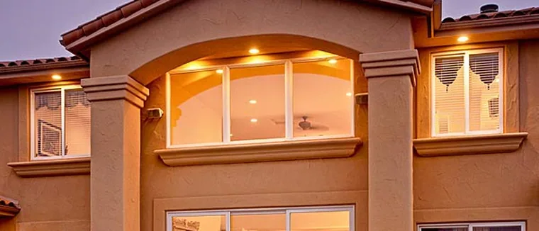 Spanish-style home at dusk with warm light through newly replaced windows