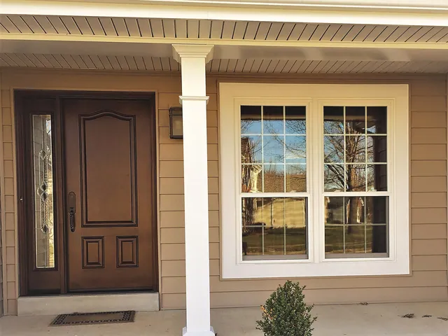 Entry with a white vinyl window alongside a stained wood door