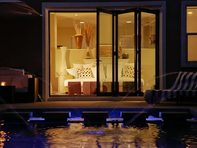 Folding glass doors lit at night beside a pool