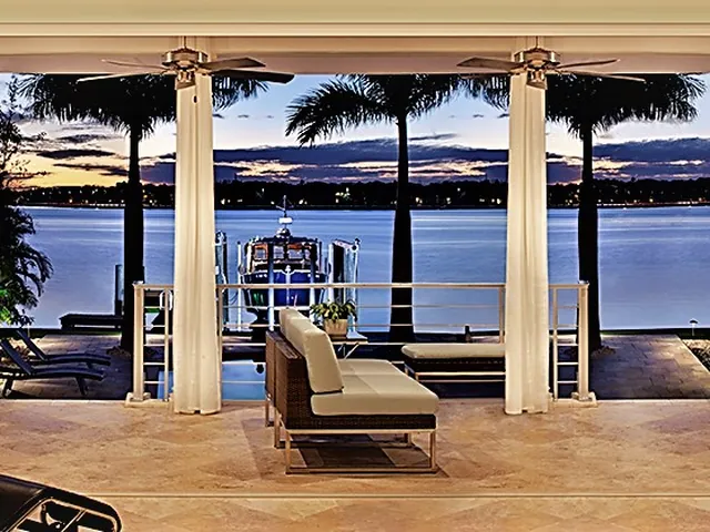 Folding doors opened to a palm-lined waterfront