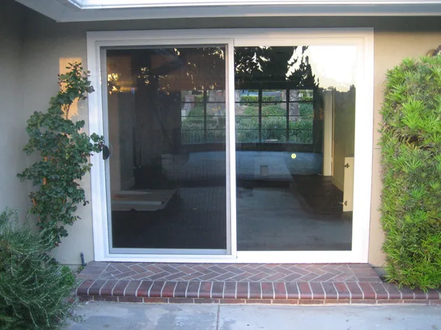 Vinyl sliding glass patio door installed in a brick rear elevation